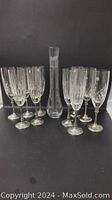 Photo showing all 10 vintage crystal champagne flutes with silver-plated stems and slim lined decanter arranged against a black background.