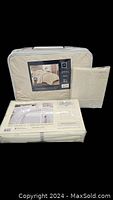 Photo showing a packaged quilted comforter set with a clear label and cream color tone