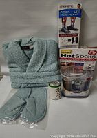 Full lot overview showing blue robe, slippers, Dr. Ho's foot and leg pain therapy device, Dr. Scholl's pedicure kit, and Hot Socks box.