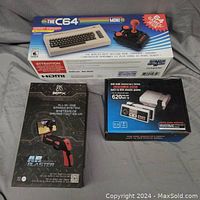 Lot showing all three boxed mini gaming systems including the C64 mini, 620 mini, and AR Blaster