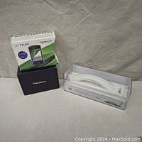 Image showing the Telus BlackBerry Storm smartphone box alongside the Curve Wireless Bluetooth Phone in sealed plastic packaging.