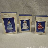 Three boxed Madame Alexander Hallmark Keepsake collectible ornaments including Elizabeth 'Beth' March, Winter Wonderland, Holiday Skater shown with soda can for scale