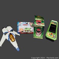 Photo showing all four toys from a birds-eye view on a black backdrop: Buzz Lightyear space vehicle (white with blue details), packaged Thomas TrackMaster Percy, boxed Power Rangers AM/FM radio, and Frogger tabletop game.