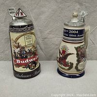 Two Anheuser-Busch steins side by side showing their overall appearance and size comparison with a soda can.