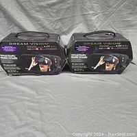 Front view of two boxed Tzumi Dream Vision VR headsets showing branding and product image.
