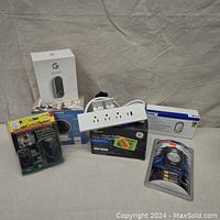 Lot showing all packaged items: Google Nest Doorbell, Honeywell Security Camera, GE Smart Plug, Coleman Motion Sensor Light, wireless remote control, and additional power strip and outlet devices.