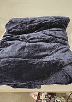 Photo showing the navy blue weighted blanket folded, highlighting the soft velvet texture and overall size.
