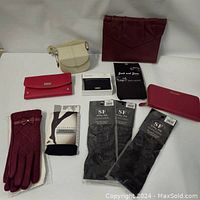 Lot contents including gloves, wallets, purses, jewelry case, and tights arranged on white surface