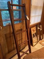 Full view of the three-quarter side of the wooden bookshelf ladder leaning against wooden door.