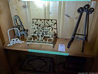 Shelf showing four different metal easels and a decorative book stand in a wood-paneled setting.