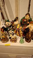 Multiple Santa figurines, snow globes, decorative trinket boxes displayed on a table