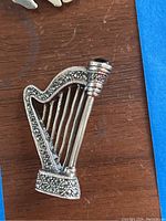 Close-up photo of the sterling silver harp-shaped pin showing front details with marcasite stones and a blue stone at the top.