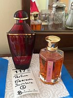 Photo showing both perfume bottles side by side on a cloth, Guerlain Samsara bottle in deep red glass and Shalimar Tubereuse octagonal bottle with gold cap.