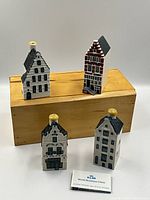 Four Blue Delft KLM ceramic collectible buildings displayed on and in front of a wooden box. Includes an information card.