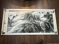 Full view of scroll laid flat on floor with metal weights at corners