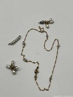 Photo showing all three items: a pearl brooch, a pair of dangle pearl earrings, and a delicate 14K gold chain necklace with small pearls spaced along the chain.
