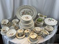 Full display of all dishware items arranged on draped surface, platter positioned at back