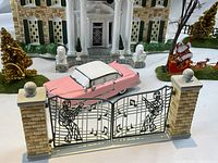 Front view of lighted ceramic Graceland mansion with pink Cadillac and metal gates