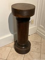 Full front view of the solid oak pedestal standing against a wall on tiled floor