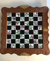 Full top view of folding chess board showing carved wood frame with dragon motifs and inlaid tile squares featuring Asian themed artwork.