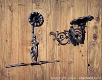 Pair of black cast iron antique Gothic wall sconces with floral and scroll designs against wood background