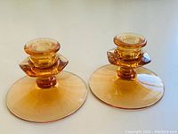 Pair of amber Fostoria candle holders side by side showing shape and color
