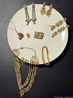 Full view of all jewelry items arranged on white plate showing necklace, earrings, brooch, and bracelet