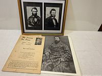 Photo showing the framed portraits, printed Louis Riel photograph, and booklet titled 'My Journey For Peace' on table.