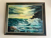 Framed oil painting of seascape with crashing waves and rocky cliffs, showing the entire artwork and frame.