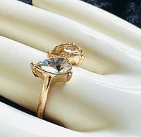 Close-up image showing the two pear-shaped stones, one clear and one amber, set in a gold tone ring band.