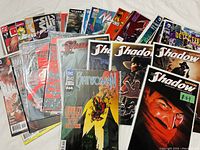 Photo showing a spread of multiple comic books including Suicide Squad, Black Panther, and The Shadow all in plastic bags with backing boards.