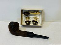 Overview of the full set showing pipe lying in front of boxed cufflinks and tie clip