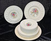 Photo of entire set with three stacked groups of plates and two plates displayed upright showing front decoration.