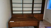 Desk positioned in front of three-unit walnut bookcase