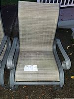 Single metal patio lounge chair with beige mesh and curved armrests, showing signs of weathering and outdoor use.