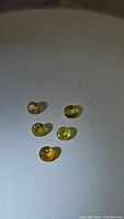 Five round cut yellow sapphires arranged on a flat surface showing various yellow hues from lemon to golden yellow.