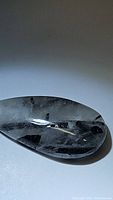 Close-up photo of the pear-shaped black rutilated quartz cabochon showing needle-like black tourmaline inclusions.