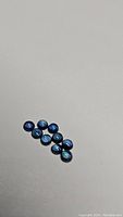 Ten round cabochon blue sapphires arranged on a light background, showing size and color uniformity.