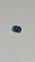 Close-up photo of the natural oval cut lagoon blue zircon gemstone showing facets and clarity.