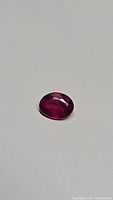 Oval cut blood red ruby on neutral background showing facets and color
