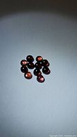 Natural garnet round cabochon gemstones on white background showing deep to light red-pink hues, total 11 stones.