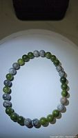 Photo of a natural green jade and map jasper beaded stretchy bracelet arranged in a circle, showing the alternating green and grey-white marbled beads.