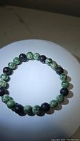 Photo showing natural green spotted jasper and black lava stone bead bracelet, round 8mm beads on stretchy cord.