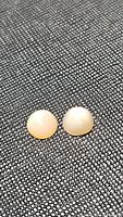 Two round cabochon peach moonstone gemstones resting on a textured black surface, showing their matched pair characteristic and smooth polished finish.
