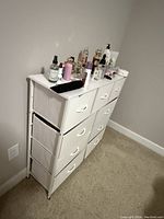 Side angled view of white dresser showing three columns of drawers and some personal items on top.