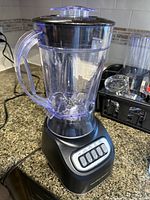 Front view of blender showing black base, control buttons, and clear pitcher with lid and handle