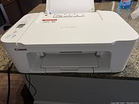 Front view of white Canon PIXMA color inkjet printer showing paper output slot and power cord.