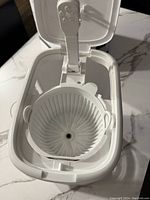 Photo of the open coffee maker showing the removable coffee filter basket inside the unit.
