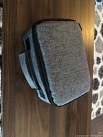 Closed gray fabric carrying case on a wooden surface.