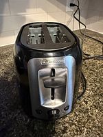 Front view of the Black+Decker toaster showing the lever, control knob, and two slots.